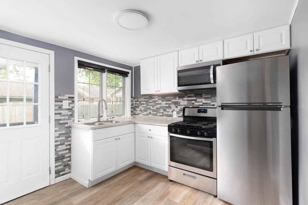 A small kitchen with white cabinets and tiled backsplash.
